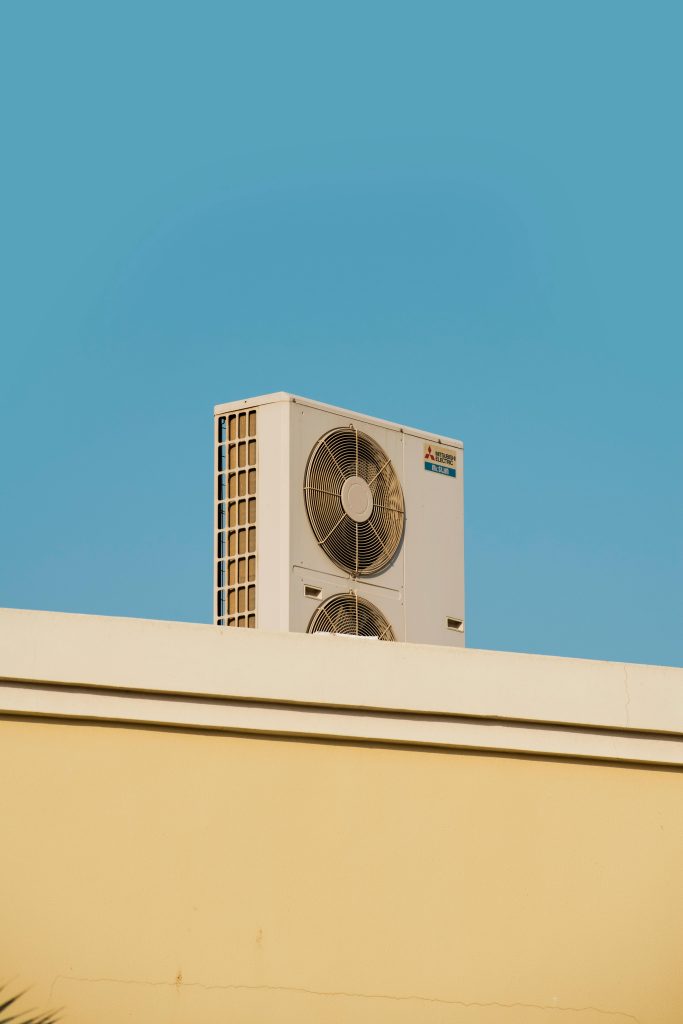 A simple and modern air conditioner unit on a rooftop with a blue sky backdrop in Dubai.